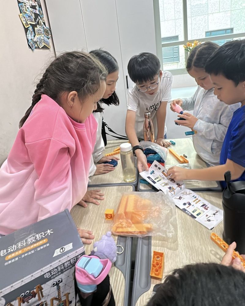 Children gather round a table, following a picture guide to build a robot from a construction kit