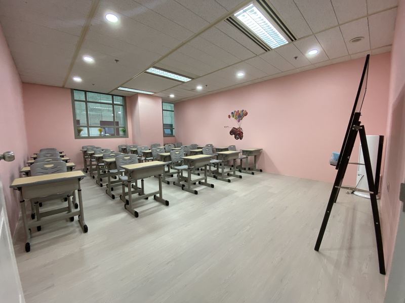 An empty classroom at a Little Earth centre with rows of single desks and a whiteboard